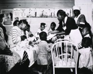 Maude Collen, an African American nurse midwife, offers instruction to new mothers in a nursery.